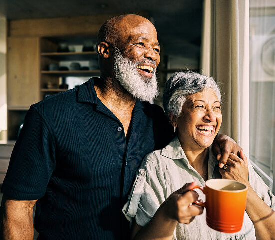 happy couple embracing by kitchen window
