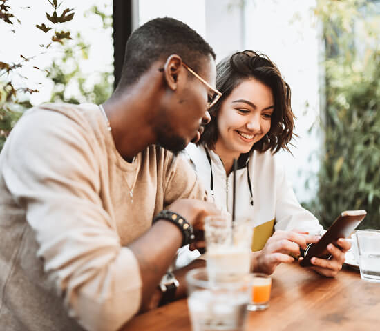 man and woman at restaurant with mobile phone